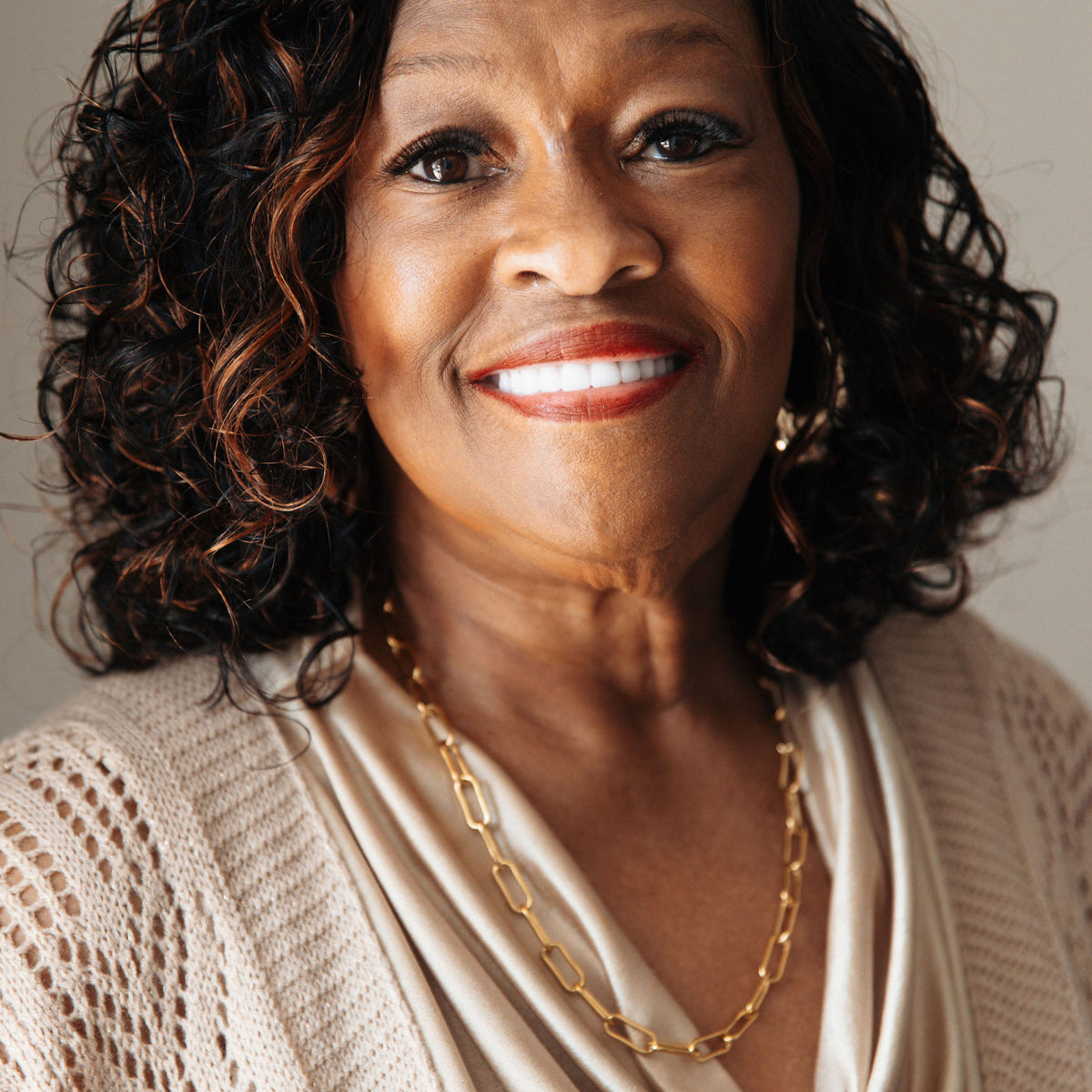 Woman wearing a gold necklace with a neutral background