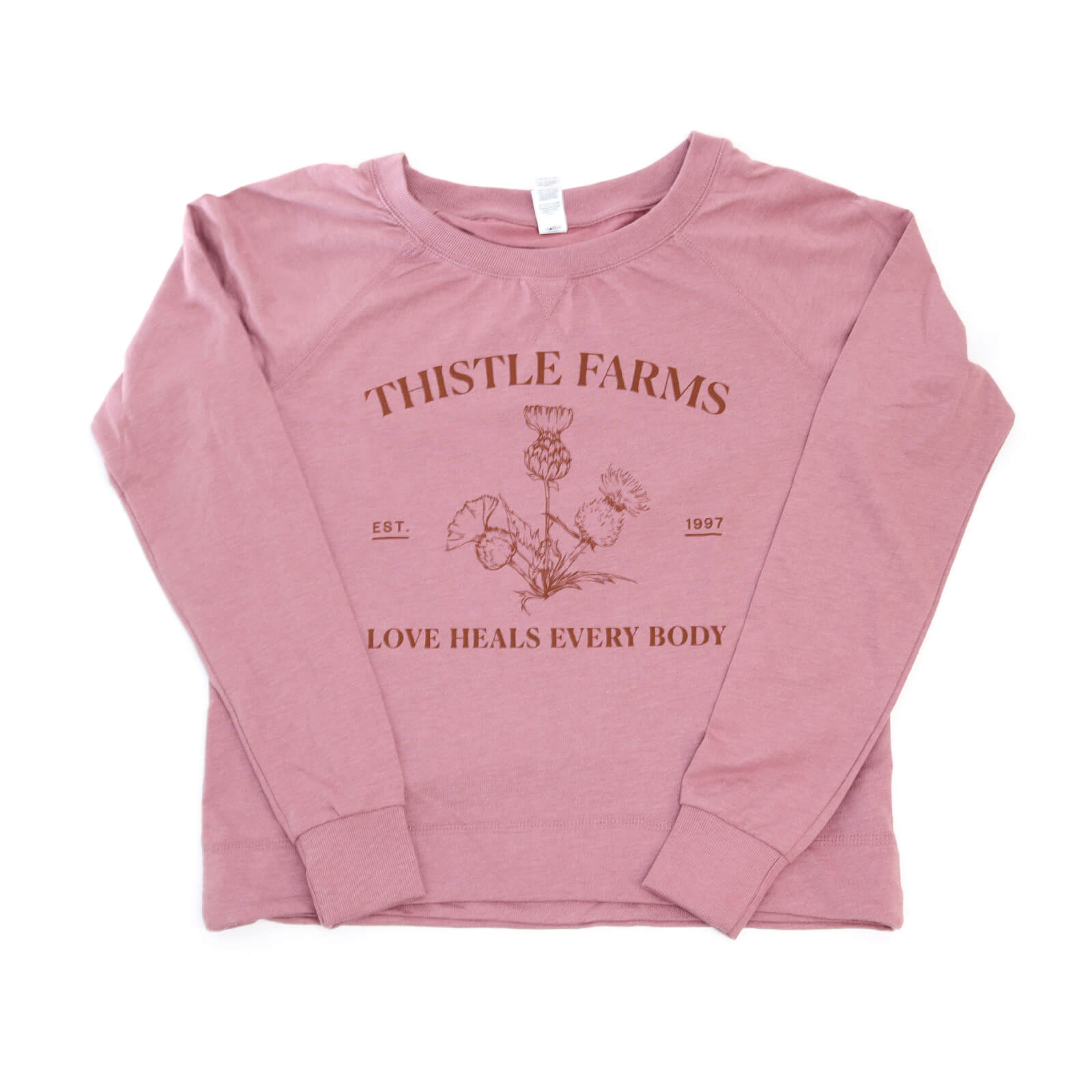 Pink long-sleeve shirt with 'Thistle Farms' branding and text on a white background