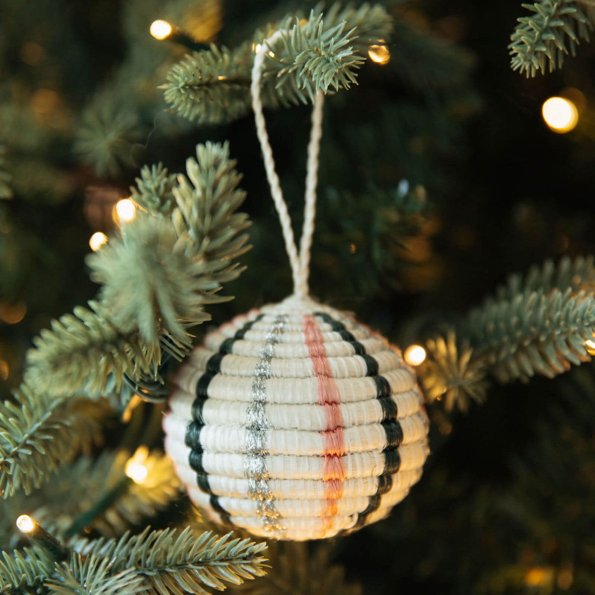 Decorative ornament with striped pattern hanging on a Christmas tree.