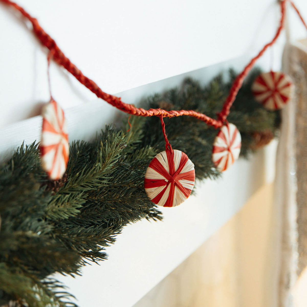 Decorative Christmas garland with peppermint candy ornaments on a white background