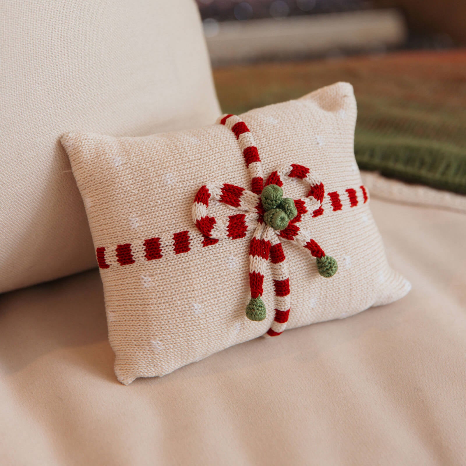 Decorative pillow with a candy cane design on a beige couch.