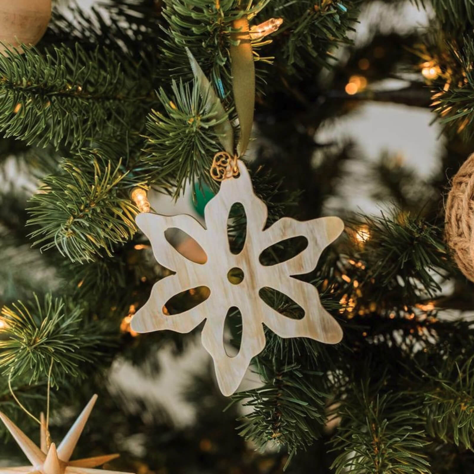 Decorative snowflake ornament on a Christmas tree with blurred lights in the background