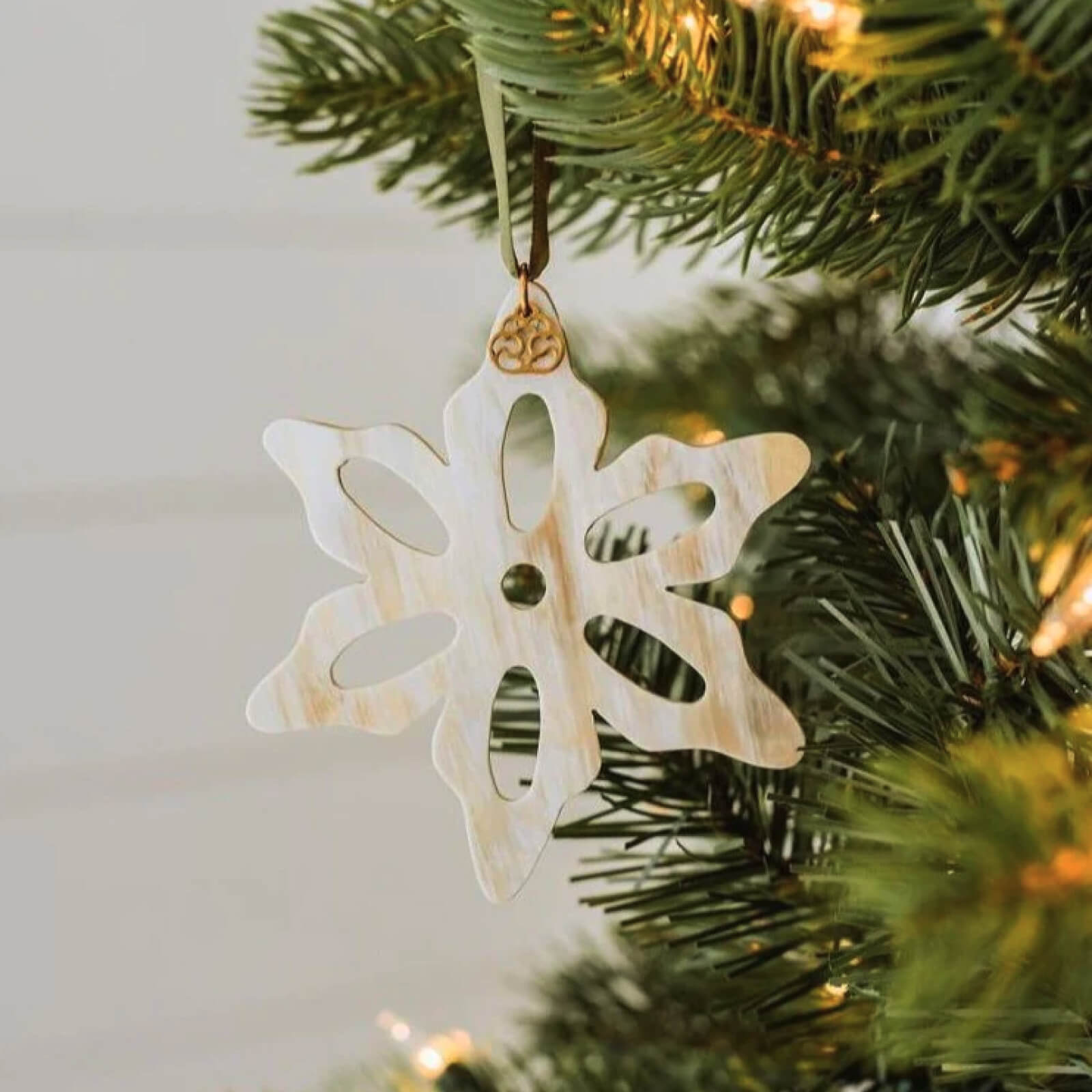 Decorative snowflake ornament hanging on a Christmas tree.