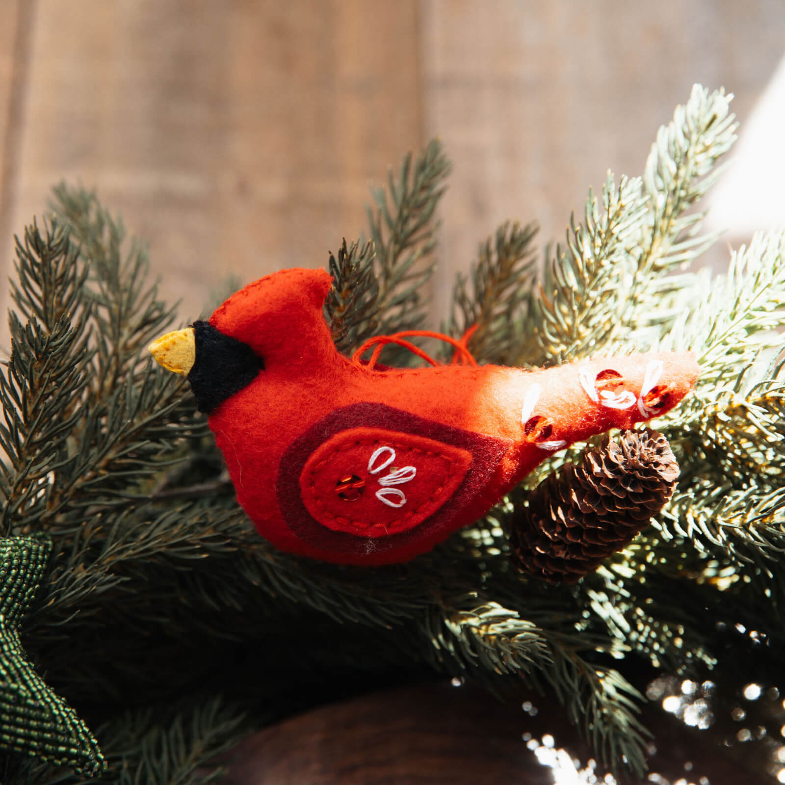 Red cardinal bird ornament on a branch with pine cones and greenery