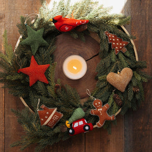Decorative wreath with candles, stars, and small figures on a wooden background