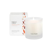 Frosted Glass Candle with Love Heals script printed on outside tumbler. Box is placed behind the candle with orange and brown petals.