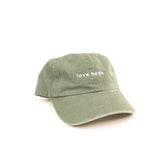 Green cap with 'love heels' text on a white background