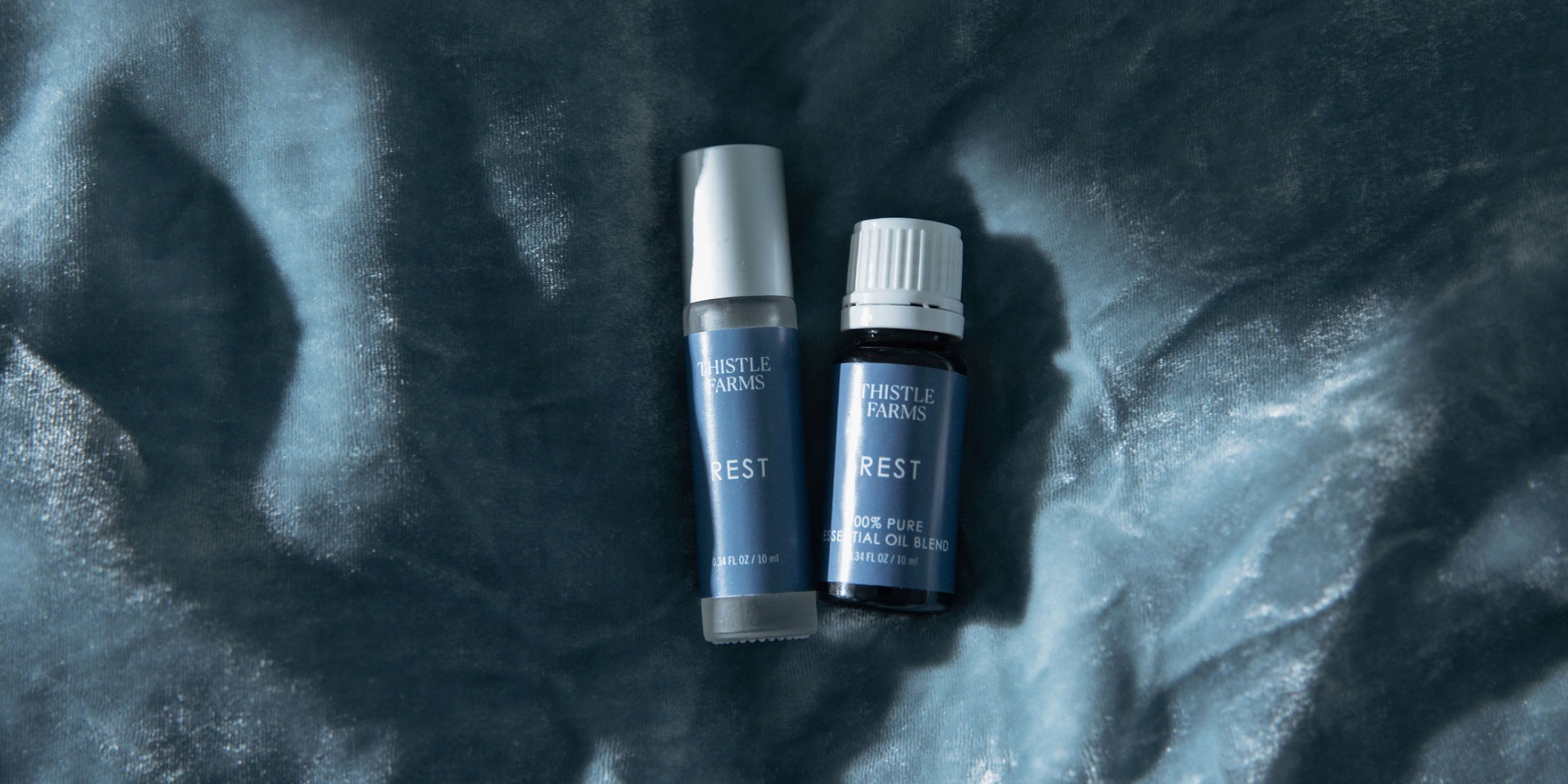 Two bottles labeled 'REST' on a textured dark surface