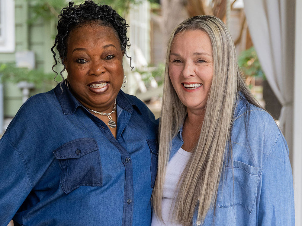 Two Thistle Farms women standing together outdoors, wearing blue shirts.