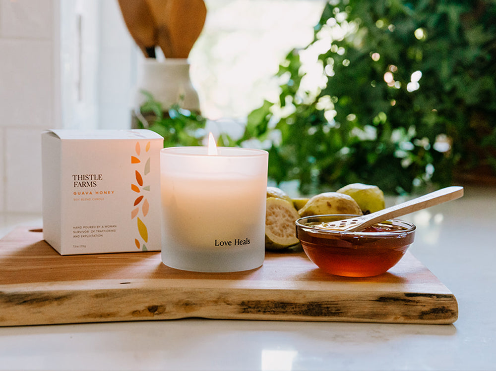 Guava Honey Candle with 'Love Heals' text on a wooden board next to guava fruit and honey.