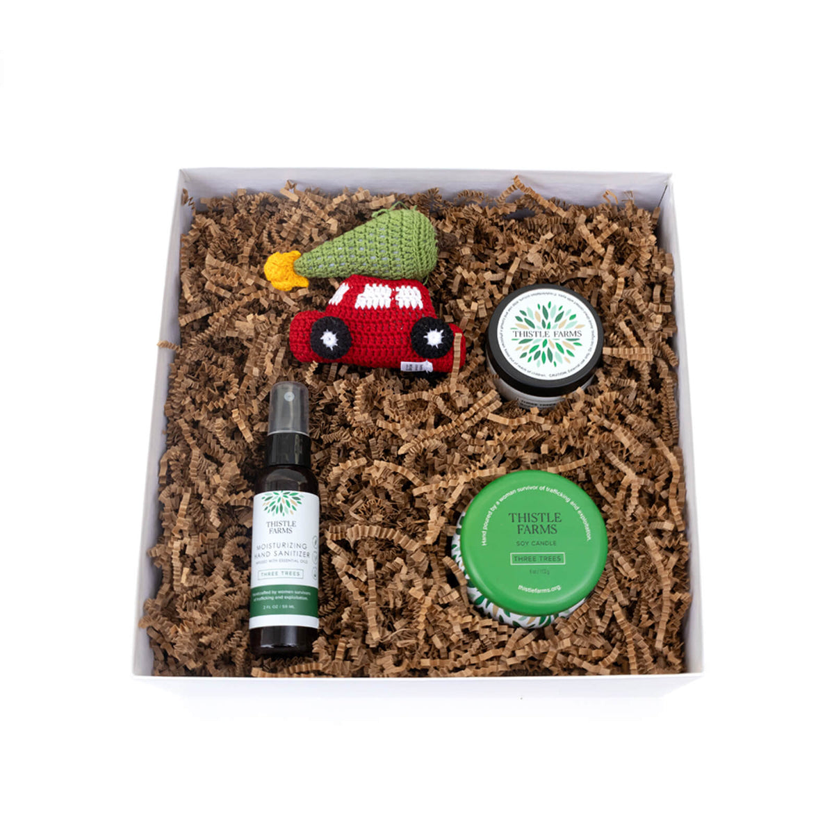 Gift set with natural products including a bottle, jar, and small toy on brown paper