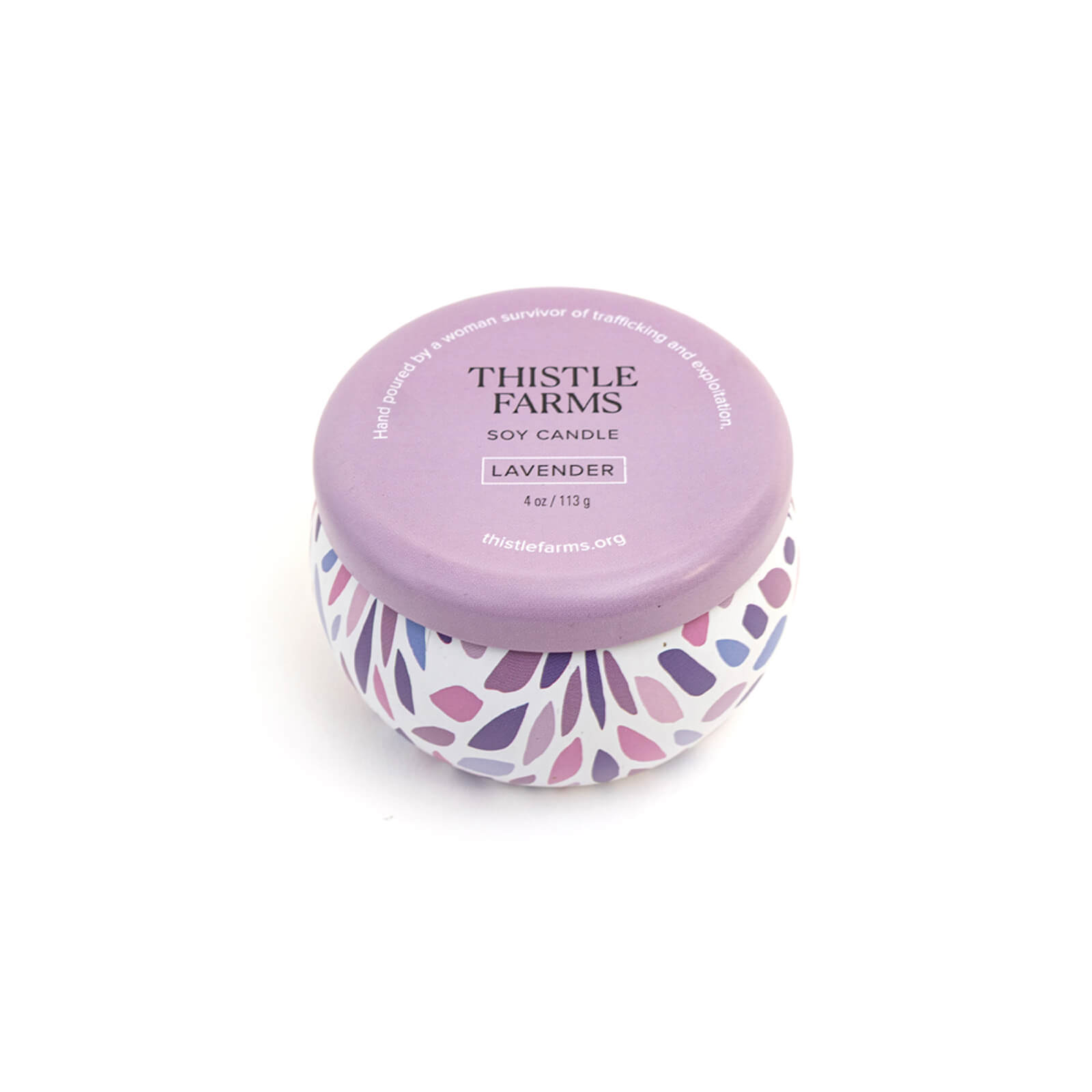 Thistle Farms soy candle with purple lid and leaf patterned base on a white background
