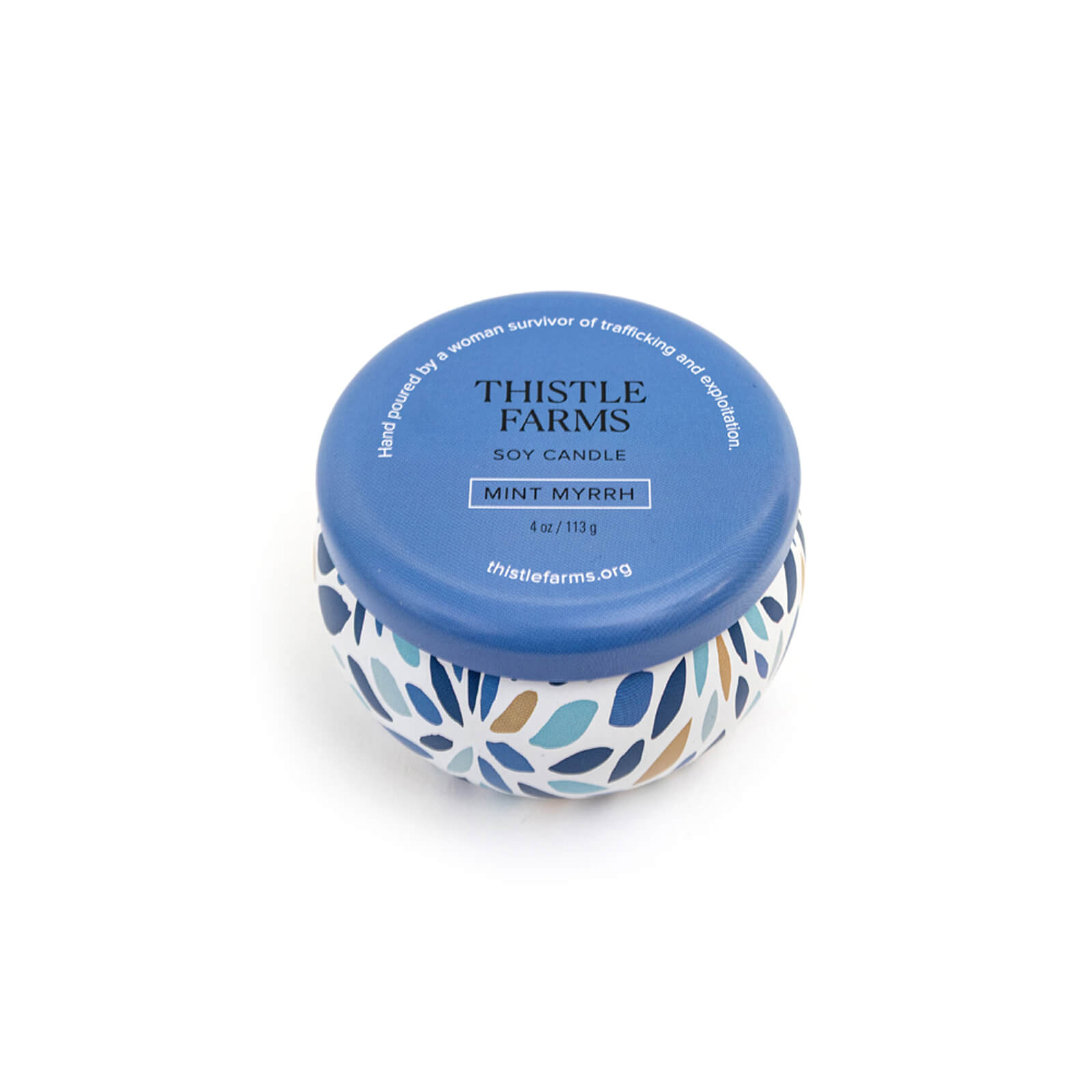 Thistle Farms soy candle with blue lid and leaf patterned container on a white background