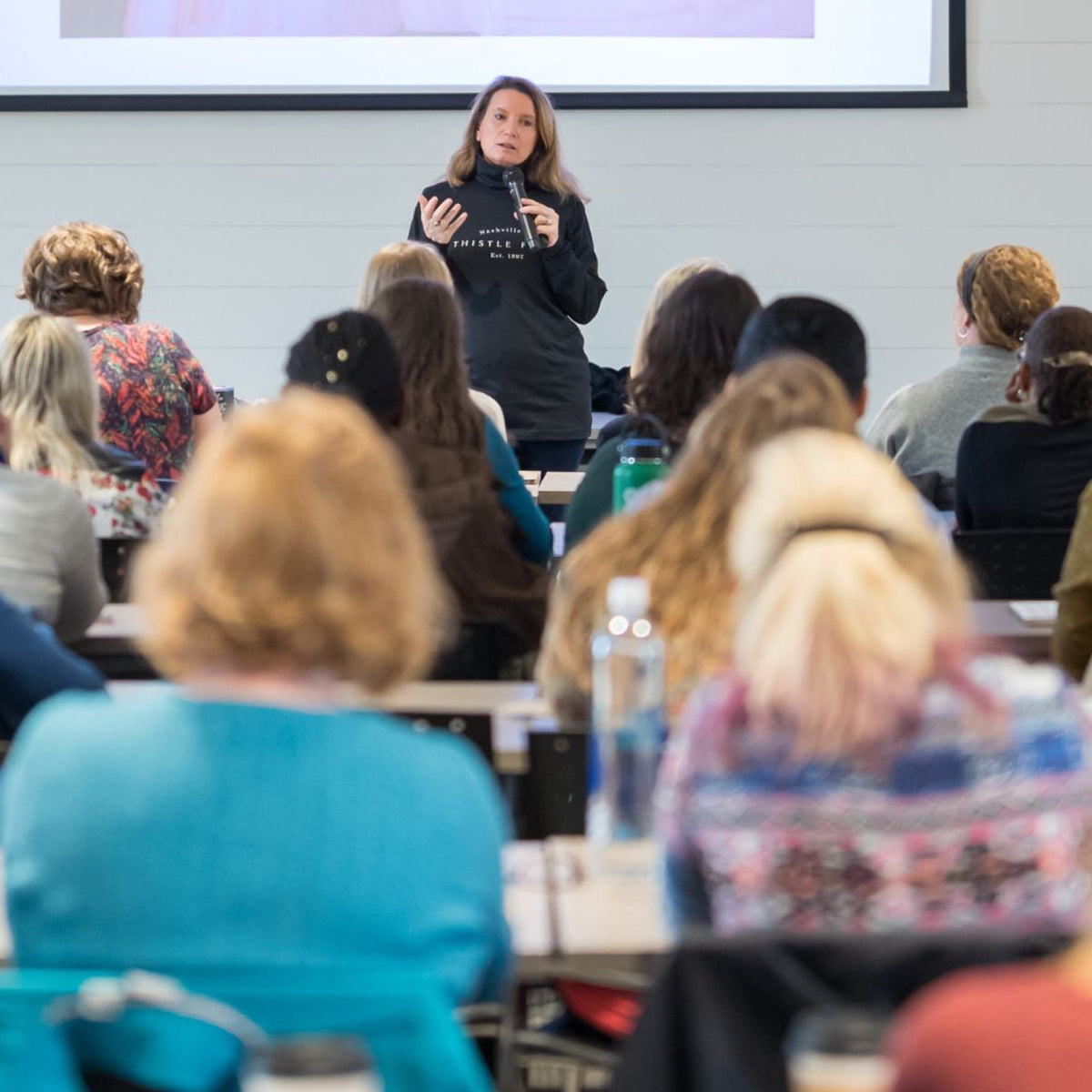 Woman giving a presentation to an audience in a classroom setting