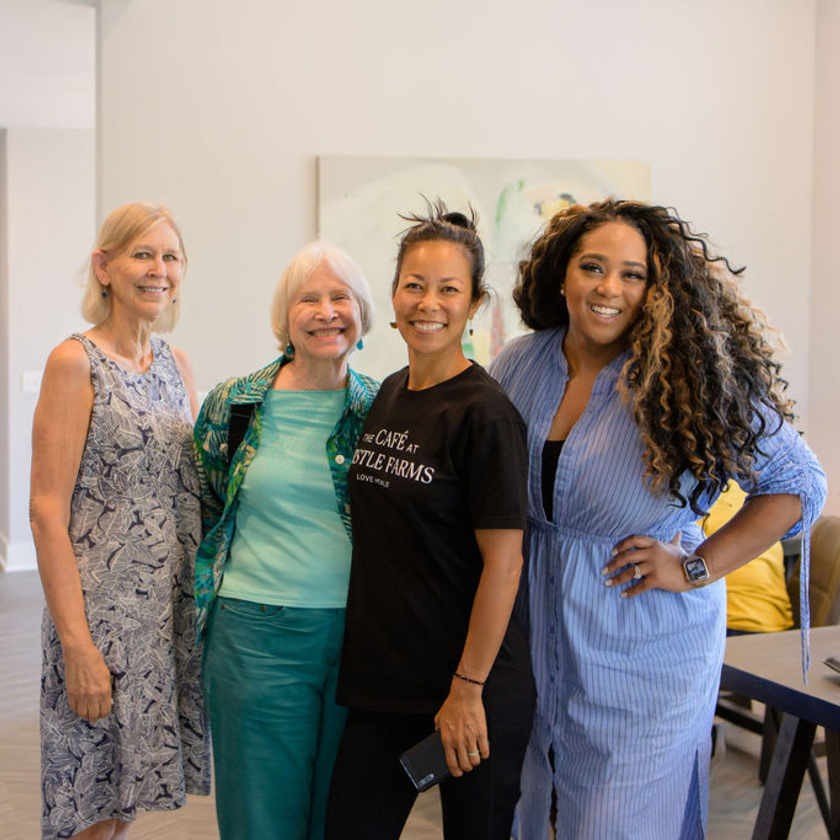 Four women posing for a photo in a modern interior setting