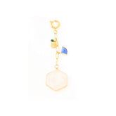 Gold charm with a white hexagonal pendant and blue and green accents on a white background