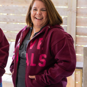 Person wearing a maroon hoodie with pink text indoors