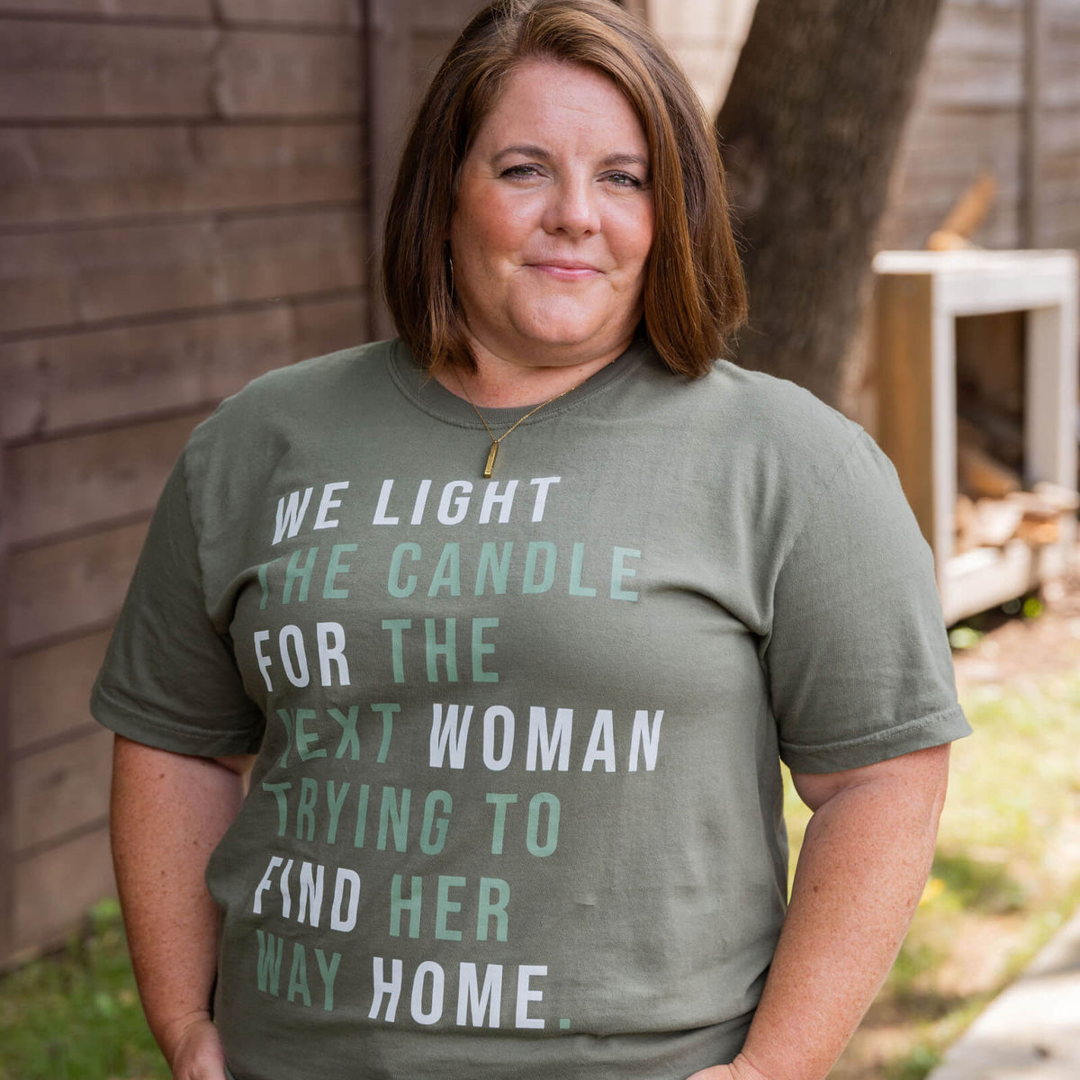 Woman wearing a green t-shirt with a printed message outdoors.