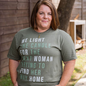 Woman wearing a green t-shirt with a printed message outdoors.