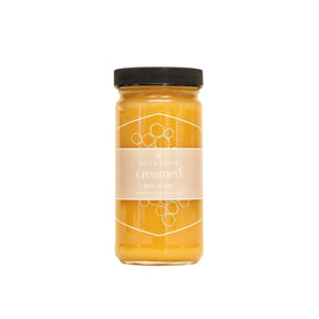 Jar of honey with a black lid on a white background