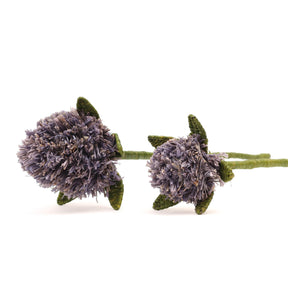 Two woven decorative flowers with purple centers and green stems on a white background
