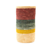 Woven vase with earthy tones of burgundy, green and yellow on a white background