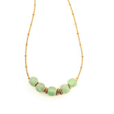 Necklace with green beads and gold accents on a white background