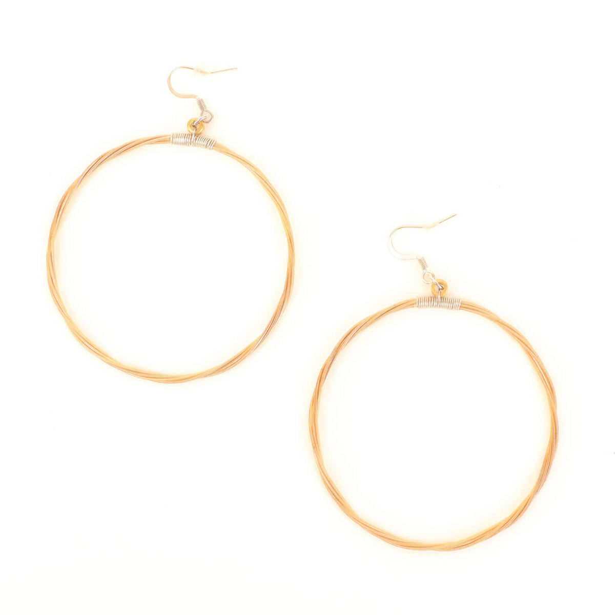 Gold hoop earrings made of guitar strings on a white background