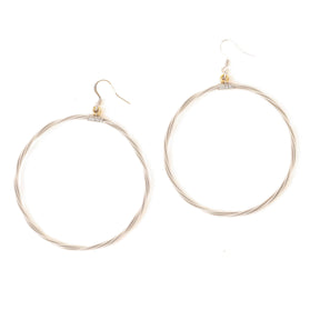 Silver hoop earrings made of guitar strings on a white background