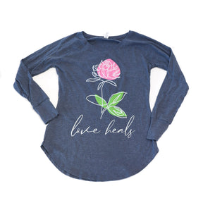 Blue long-sleeve shirt with a pink flower and 'love heals' text on a white background
