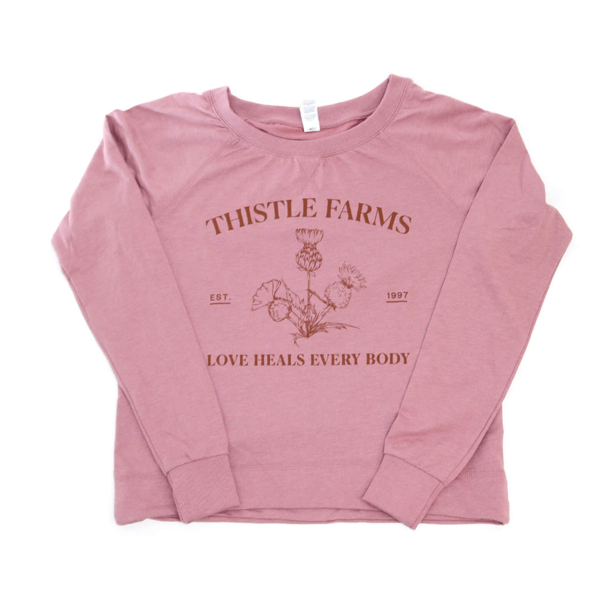 Pink long-sleeve shirt with 'Thistle Farms' branding and text on a white background