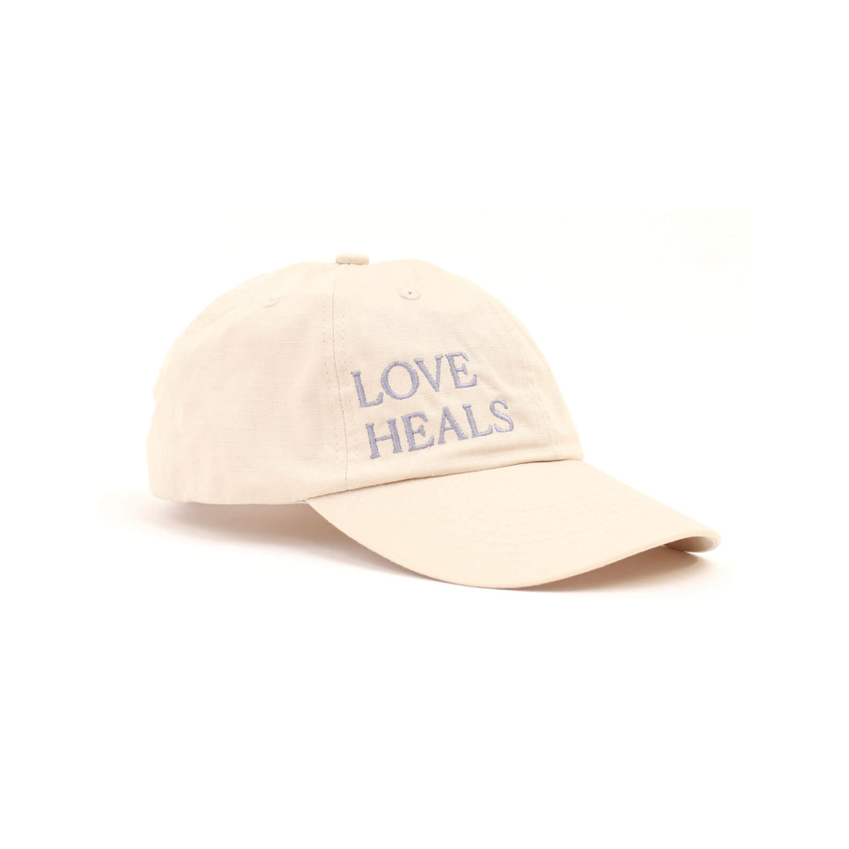 Beige cap with 'LOVE HEALS' text on a white background