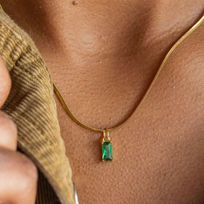 Gold necklace with a green pendant on a person's neck