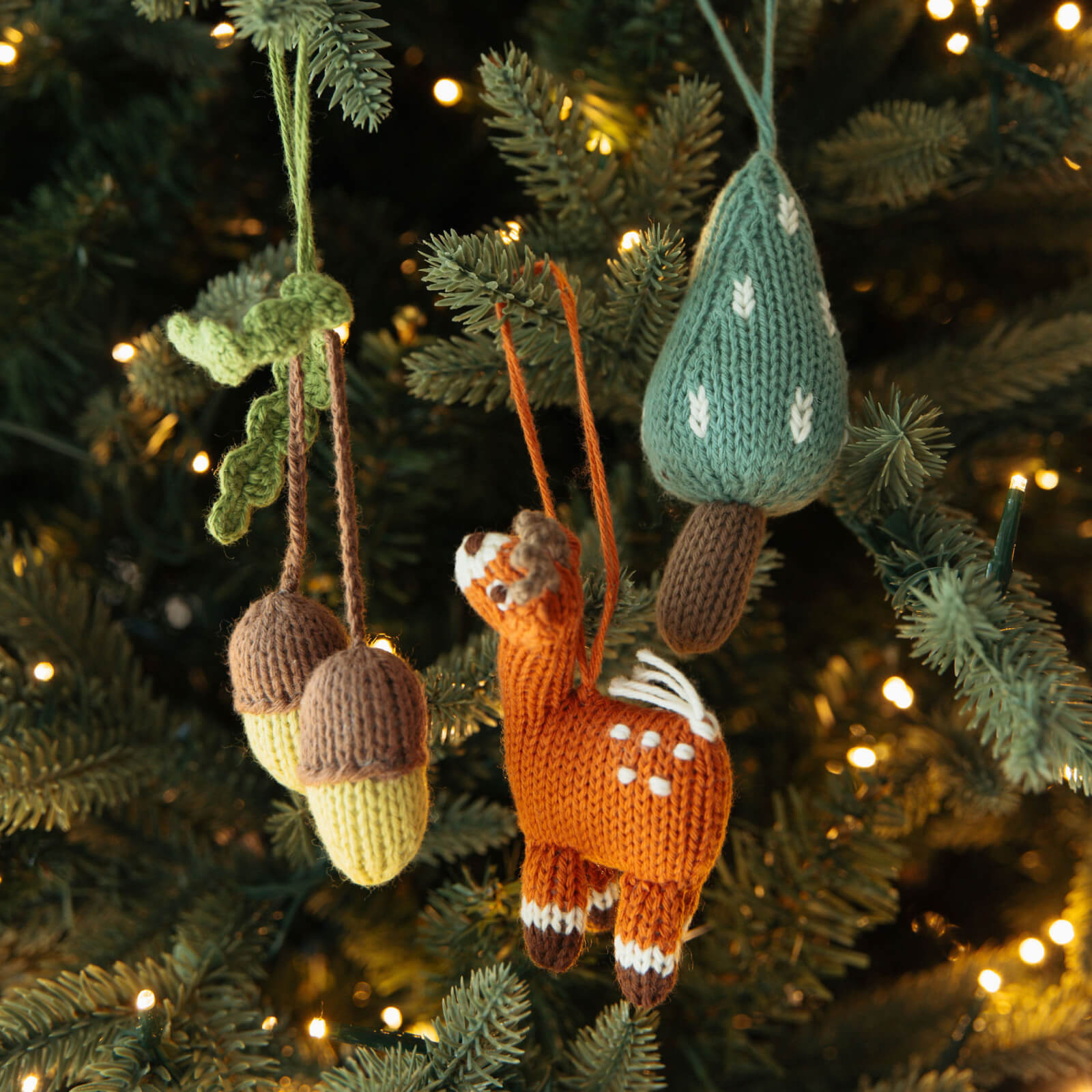 Christmas ornaments including acorns, a tree and a deer hanging on a christmas tree.