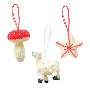 Three knitted ornaments: a mushroom, a star, and a lamb, on a white background.