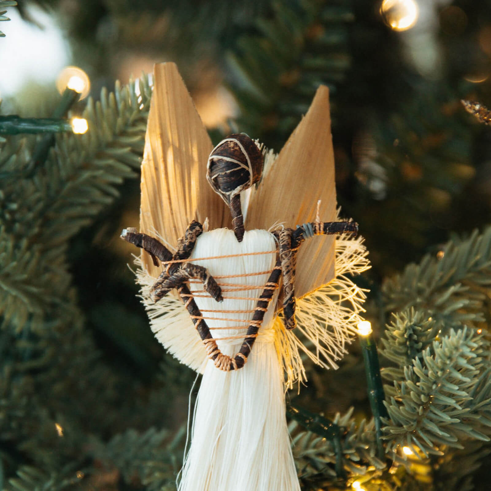 Decorative angel ornament on a Christmas tree with blurred lights in the background