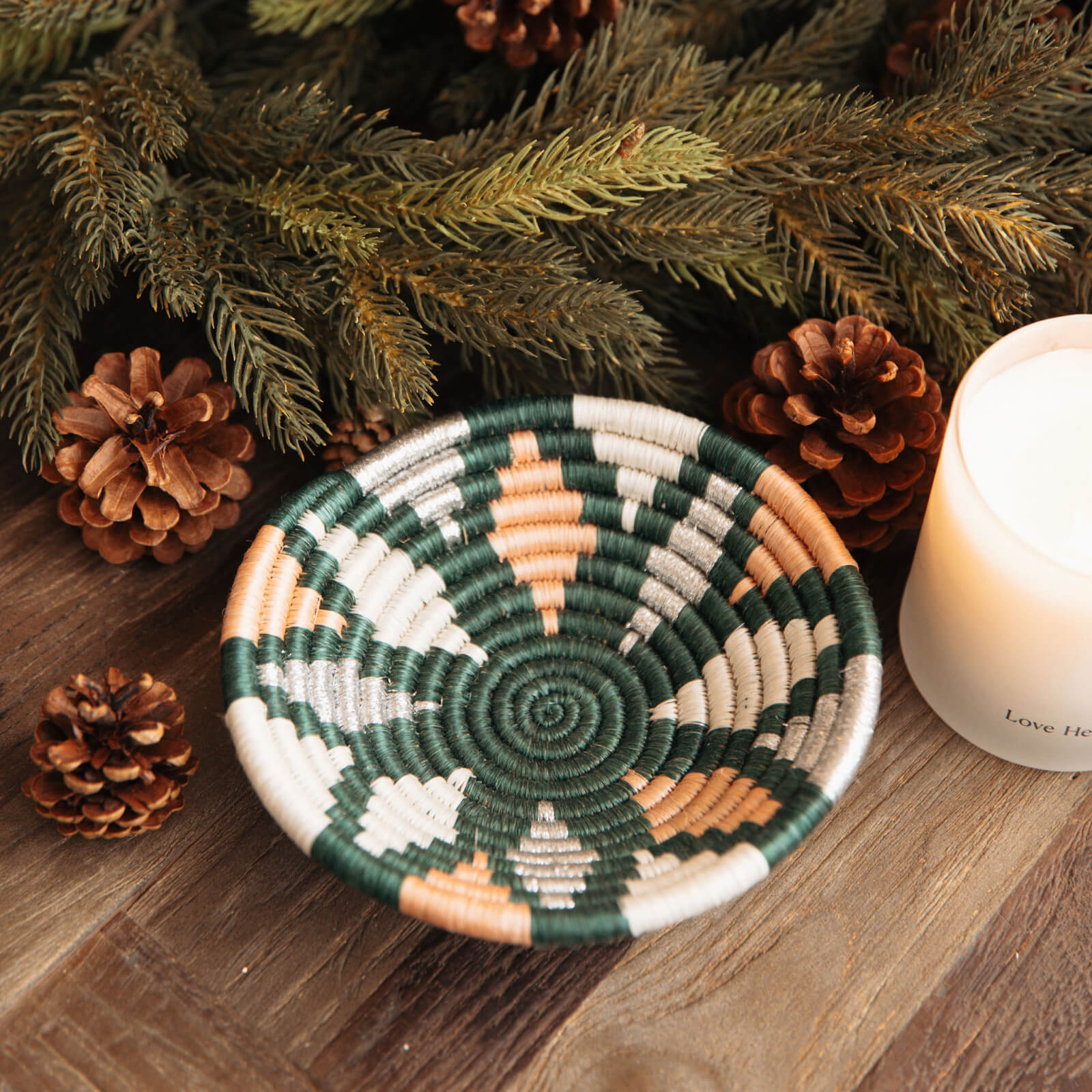 Woven basket with geometric pattern on a wooden surface with pine cones and a candle.