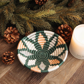 Woven basket with geometric pattern on a wooden surface with pine cones and a candle.
