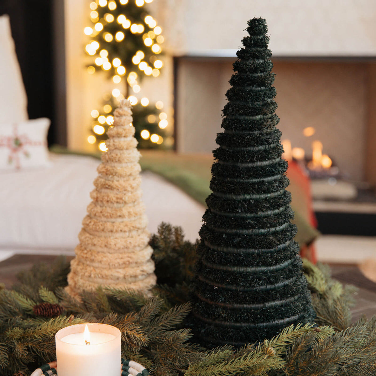 Decorative Christmas trees on a table with a candle and blurred festive background