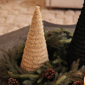 Textured cone-shaped Christmas tree on a bed of greenery with pine cones.