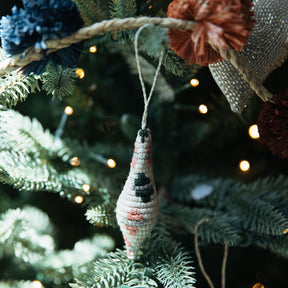 Decorative ornament hanging on a Christmas tree with lights in the background