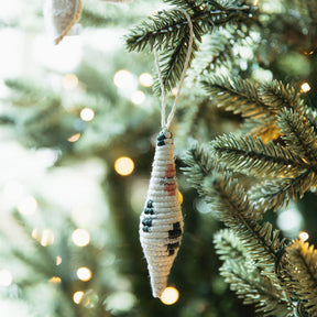 Decorative icicle ornament hanging on a Christmas tree with blurred lights in the background