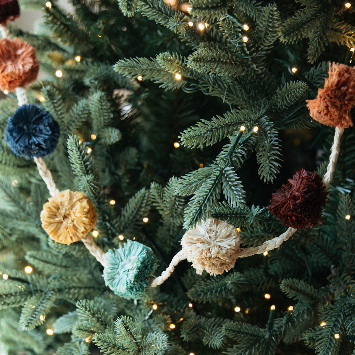 Decorative garland with multicolored pom-poms on a Christmas tree.