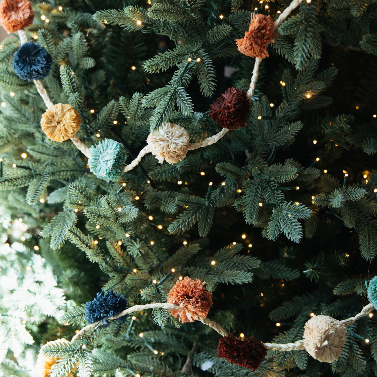 Decorative garland with colorful pom-poms on a Christmas tree