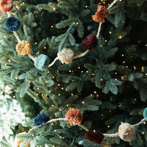 Decorative garland with colorful pom-poms on a Christmas tree