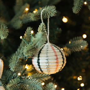 Decorative ornament on a Christmas tree with lights in the background