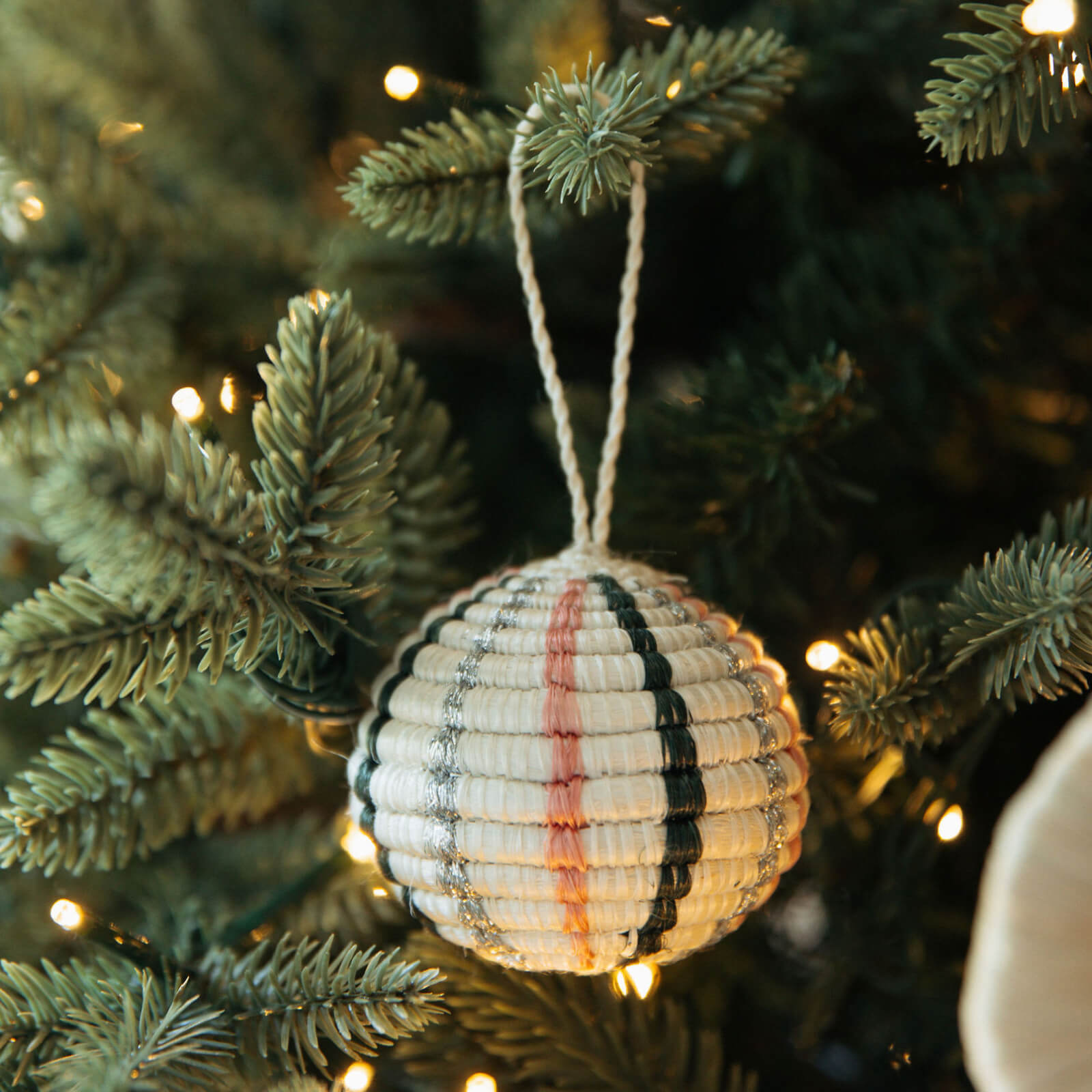 Decorative ornament with striped pattern hanging on a Christmas tree.