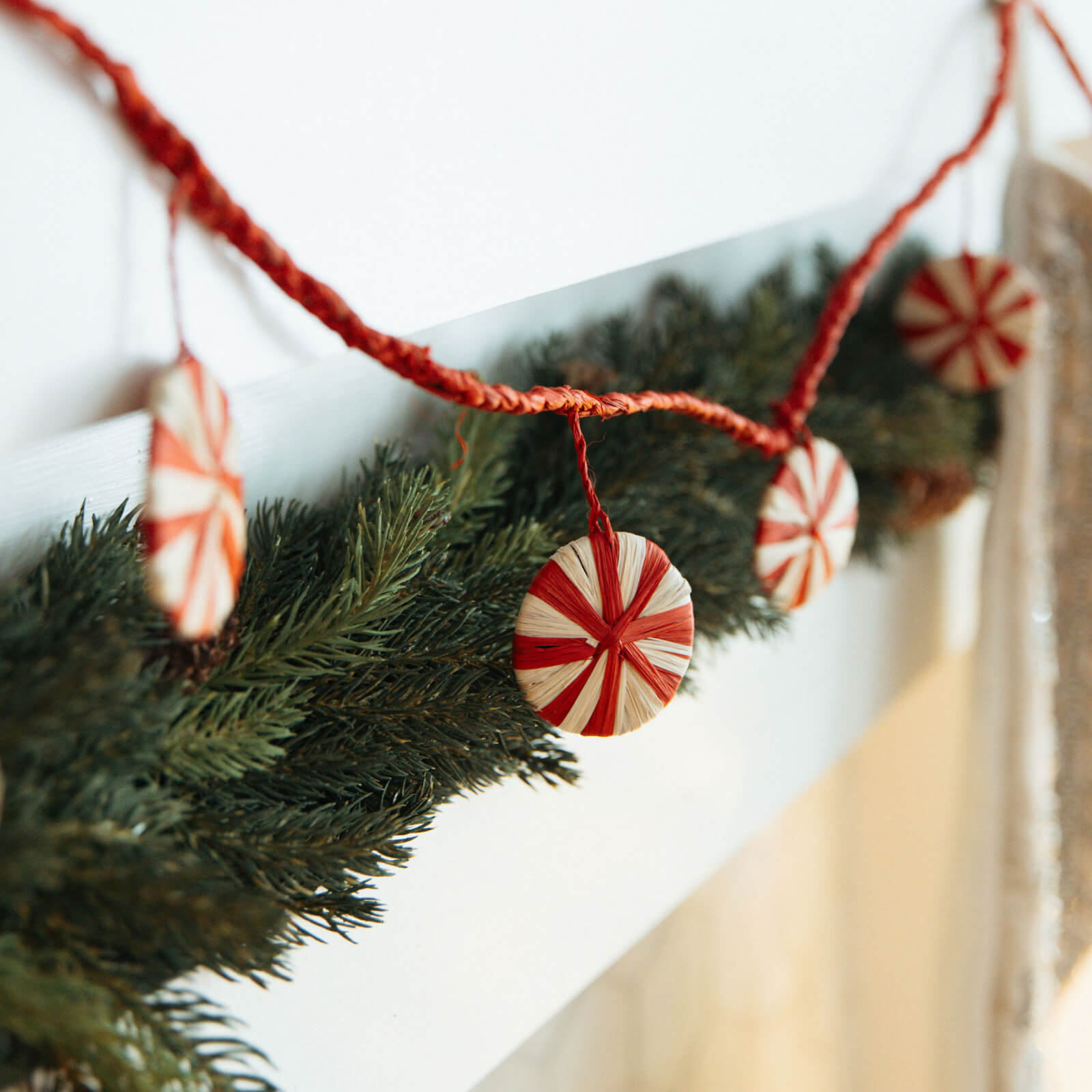 Decorative Christmas garland with peppermint candy ornaments on a white background