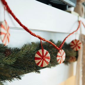 Decorative garland with peppermint candy ornaments on a Christmas tree.