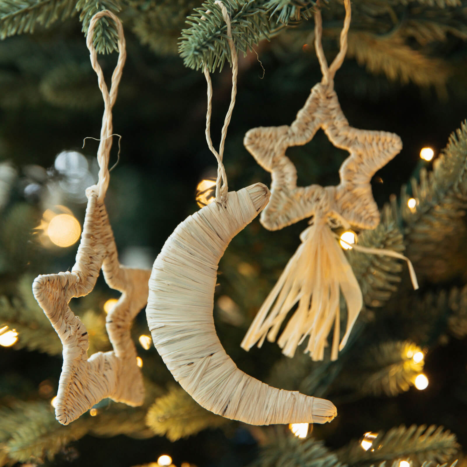 Decorative moon and star ornaments hanging on a Christmas tree.